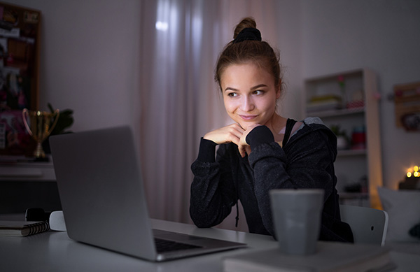 Beautiful happy young girl with laptop sitting and smiling, online dating concept.